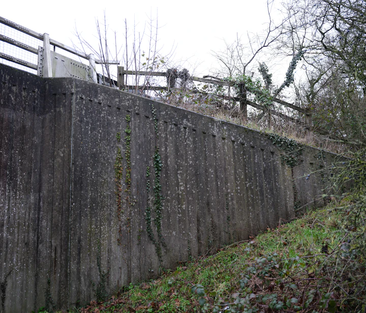 Tall concrete retaining wall along a sloped path
